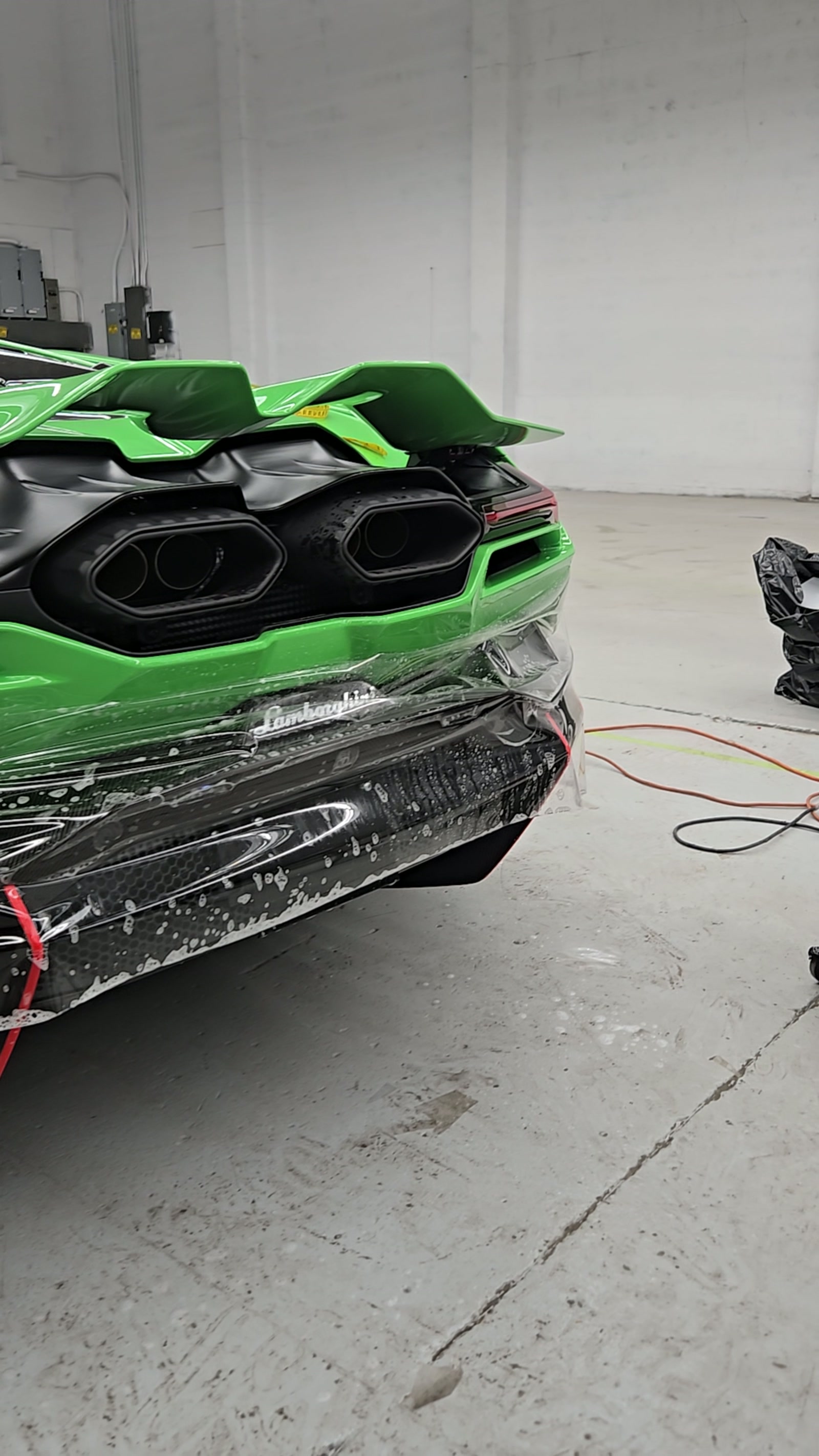 Green Lamborghini with paint protection film being installed on the rear bumper